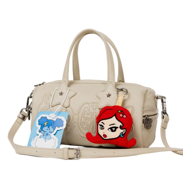 A beige faux-leather handbag with embossed floral details, featuring a red-haired cartoon character patch on the front, a blue dog charm, and a matching beige shoulder strap on a white background.